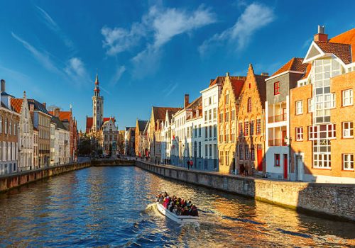 Tourist boat on canal Spiegelrei and Jan Van Eyck Square in the morning in Bruges, Belgium