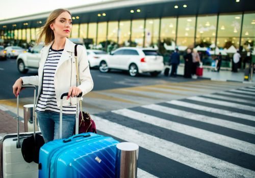 stunning-blonde-lady-with-blue-white-suitcases-stands-before-crossing-street